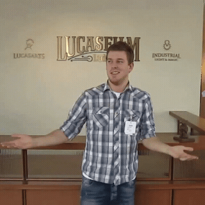 Man In Plaid Shirt Standing In Front Of Lucasfilm Sign GIF