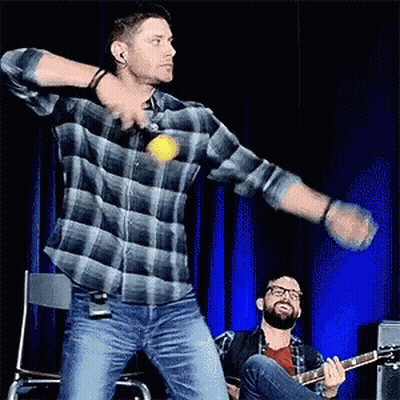 Man In Plaid Shirt Throwing Ball While Another Plays Guitar GIF