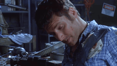 Man In Plaid Shirt Working In Dark Room With Danger Sign GIF