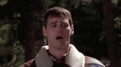 Man In Plaid Sweater And Tie Standing In Front Of Trees GIF
