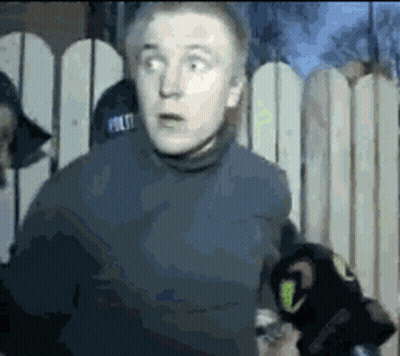 Man In Police Hat In Front Of Fence GIF