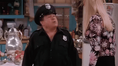Man In Police Hat Talking To Woman In Kitchen GIF