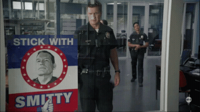 Man In Police Uniform In Front Of Stick With Smithy Sign GIF
