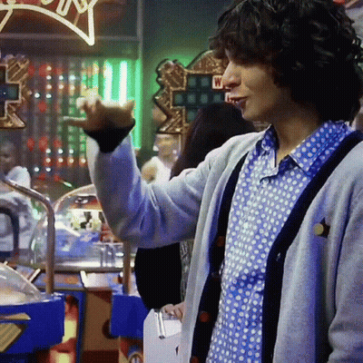 Man In Polka Dot Shirt And Gray Cardigan Standing By Lucky Star Sign GIF