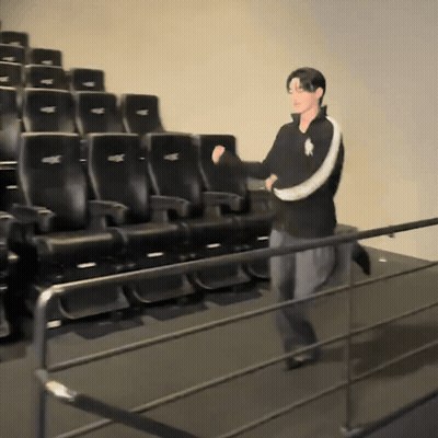 Man In Polo Shirt In Front Of Black Theater Seats GIF
