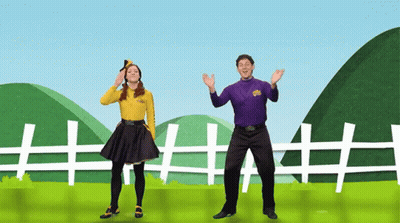 Man in Purple and Woman in Yellow Dancing in Front of Fence