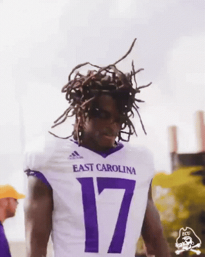 Man In Purple ECU Shirt Holding Up Fist GIF