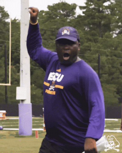 Man In Purple ECU Shirt Holding Up Fist GIF