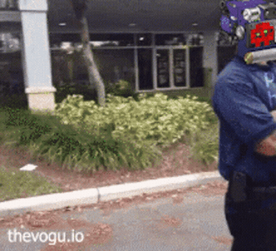 Man In Purple Helmet Walking Down Street With Thevogu.io GIF