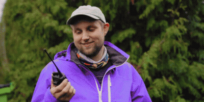 Man In Purple Jacket And Hat Holding Walkie Talkie GIF