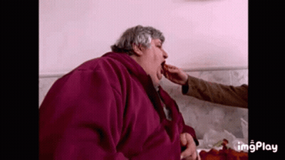 Man In Purple Jacket Eating From Hand GIF