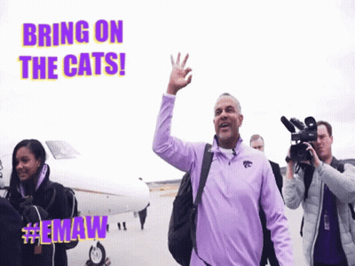 Man In Purple Jacket Waving In Front Of Plane Saying Bring On The Cats GIF