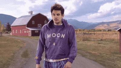 Man In Purple Moon Sweatshirt Walking Down Dirt Road GIF