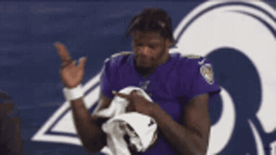 Man In Purple Ravens Shirt Holding White Towel GIF