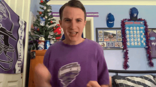Man In Purple Shirt In Front Of Hurricanes Poster GIF