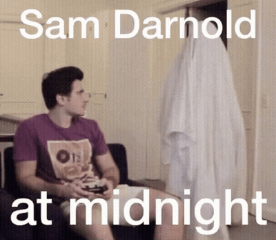 Hombre de camisa morada jugando videojuego con fantasma detrás GIF