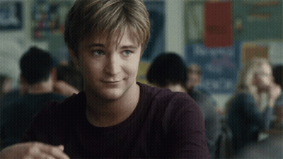 Man In Purple Shirt Smiling In Front Of New York Sign GIF