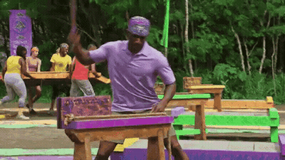 Man In Purple Shirt Standing Next To Wooden Table In Woods GIF
