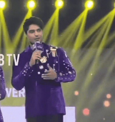 Man In Purple Suit Holding Microphone In Front Of BTV Logo GIF
