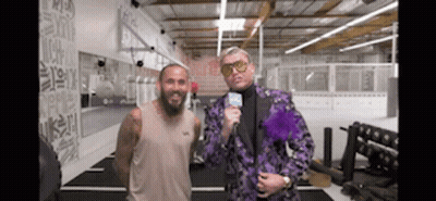 Man In Purple Suit Next To Man In Tan Tank Top In Gym GIF