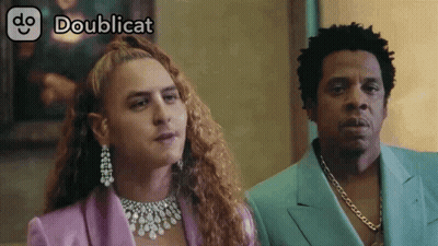 Man In Purple Suit Next To Woman With Necklace GIF