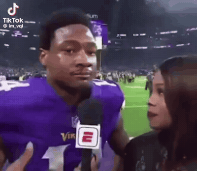 Man In Purple Vikings Jersey Talking To Woman With Microphone GIF