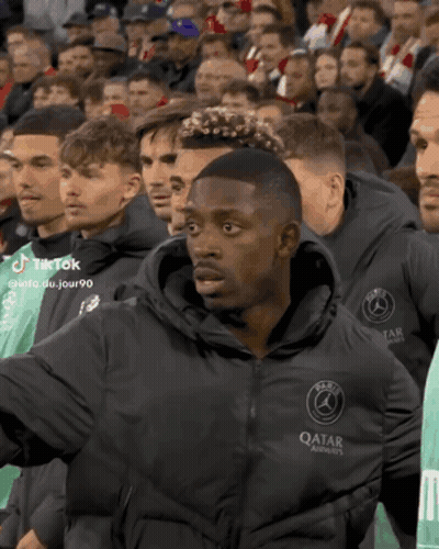 Man In Qatar Jacket Standing In Crowd GIF