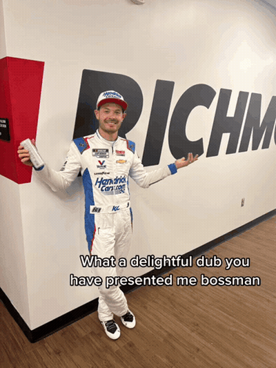 Man In Racing Suit Facing Wall Saying Richm GIF