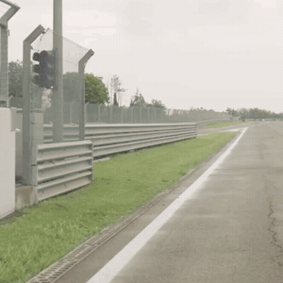 Man In Racing Suit Walking Down Race Track GIF