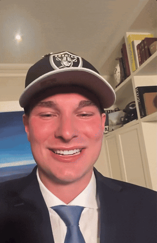 Man In Raiders Hat And Tie Smiles GIF