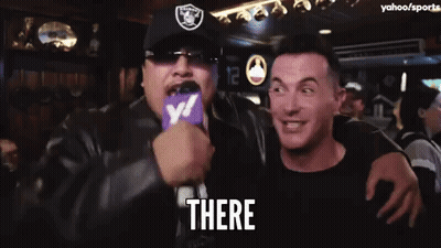 Man In Raiders Hat Holding Microphone Saying There GIF