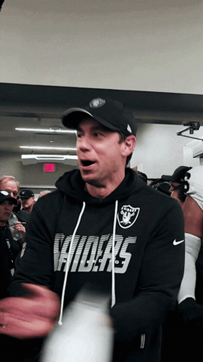 Man In Raiders Sweatshirt Standing In Crowd GIF