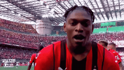 Man In Red And Black Striped Shirt In Front Of Futball Stadium GIF