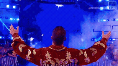 Man In Red And Gold Sweater Standing On Stage GIF