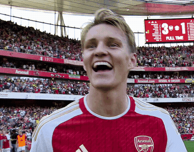 Man In Red And White Arsenal Jersey Laughing In Front Of Crowd GIF