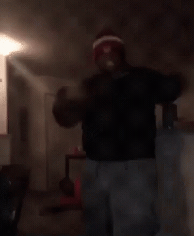 Man in Red and White Hat Dancing in Living Room With Woman on Floor