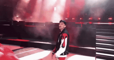 Man In Red And White Jacket On Stage Before Crowd GIF