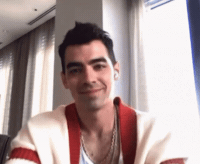 Man In Red And White Sweater Smiling At Table By Window GIF