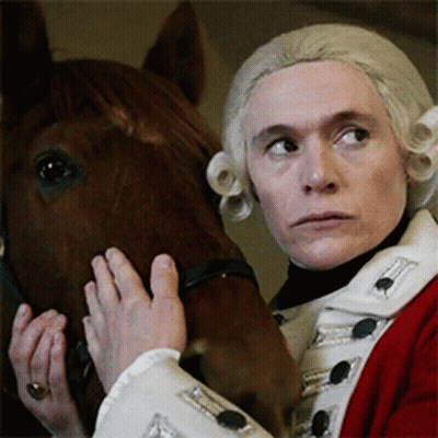 Man In Red And White Uniform Holding Brown Horse GIF