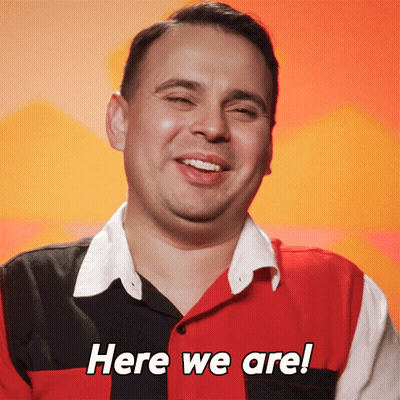 Man In Red Black And White Shirt Smiling Saying Here We Are GIF