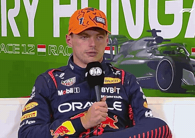 Man In Red Bull Jacket Holding Microphone In Front Of Ace 12 Race Sign GIF