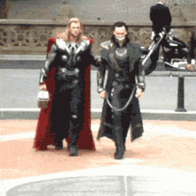 Man In Red Cape Walking Next To Man In Black Suit GIF
