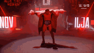 Man In Red Coat In Front Of Nov Sign GIF