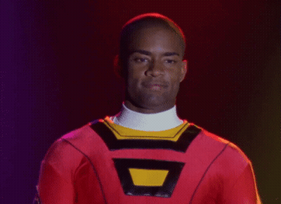 Man In Red Costume With Yellow Triangle Smiling GIF