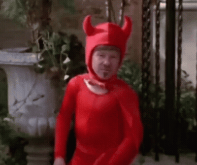 Man In Red Devil Costume With Horns And Potted Plant GIF