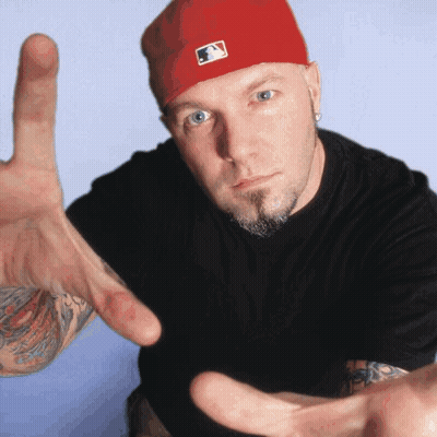 Man In Red Hat And Black Shirt Reaching Out GIF