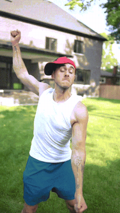 Man In Red Hat And White Tank Top Standing In Grass GIF