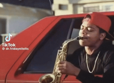 Man In Red Hat Playing Saxophone In Front Of Car GIF
