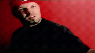 Man In Red Hat Standing Before Red Wall GIF