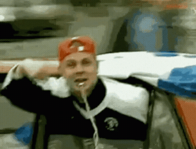 Man In Red Hat Sticking Tongue Out In Car GIF